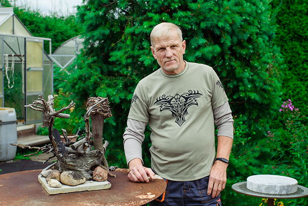 Natural Pharmaceuticals VitaSolaris® D3 Keskealine mees seisab aiaplaadil, kõrval on looduslikust materjalist käsitöödekoratsioon ja taustal rohelised puud.