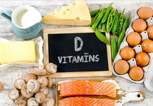 Natural Pharmaceuticals VitaSolaris® D3 D-vitamiini rikkad toidud: munad, lõhe, juust, või, piim, herned ja seened puidust laual.